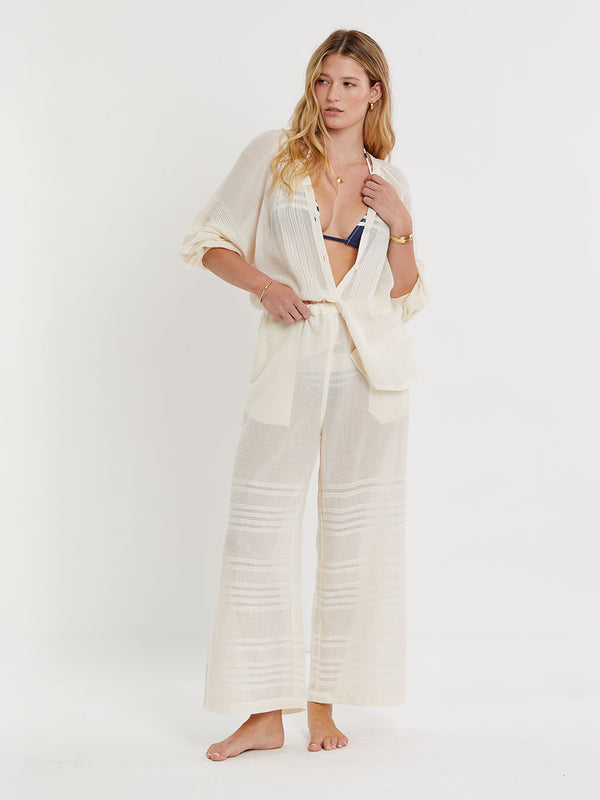 Woman standing wearing lemlem handwoven DESTA Pants featuring extra light gauzy cotton in a delicate cream color.