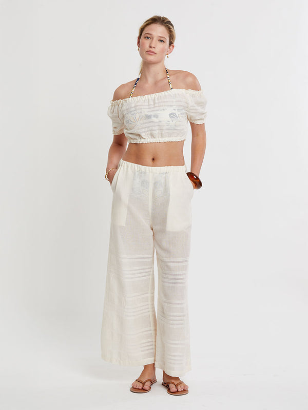Woman standing wearing lemlem handwoven DESTA Pants featuring extra light gauzy cotton in a delicate cream color.