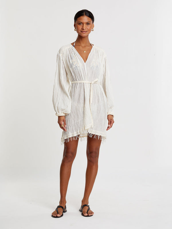 Woman standing wearing lemlem handwoven FASIKA Dress featuring extra light gauzy cotton in a delicate cream color.