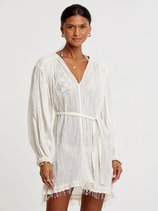 Woman standing wearing lemlem handwoven FASIKA Dress featuring extra light gauzy cotton in a delicate cream color.