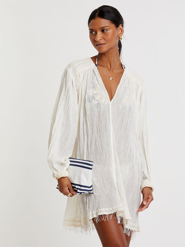 Woman standing wearing lemlem handwoven FASIKA Dress featuring extra light gauzy cotton in a delicate cream color.