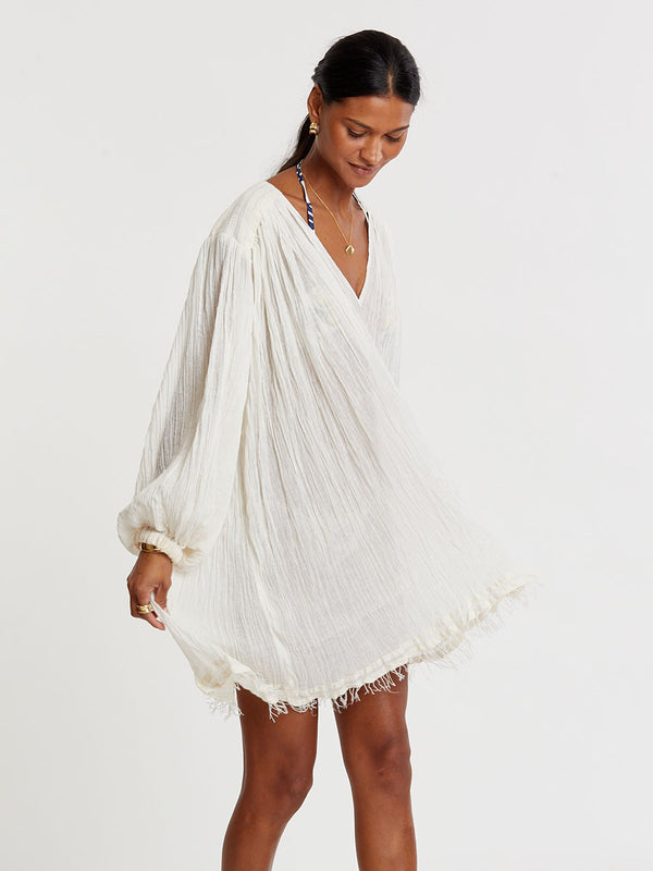 Woman standing wearing lemlem handwoven FASIKA Dress featuring extra light gauzy cotton in a delicate cream color.