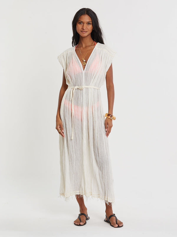 Woman standing wearing lemlem handwoven JANENE Dress featuring extra light gauzy cotton in a delicate cream color.