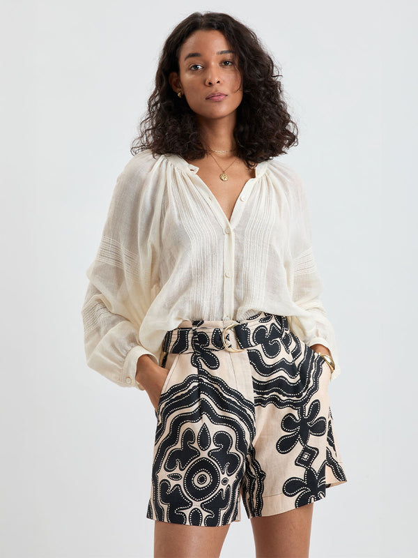 Woman standing wearing lemlem MITA Handwoven blouse featuring sheer fabric in cream color