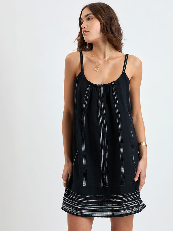 woman standing wearing lemlem handwoven ZINA Swing Dress dress featuring white dotted pattern in white color on black background