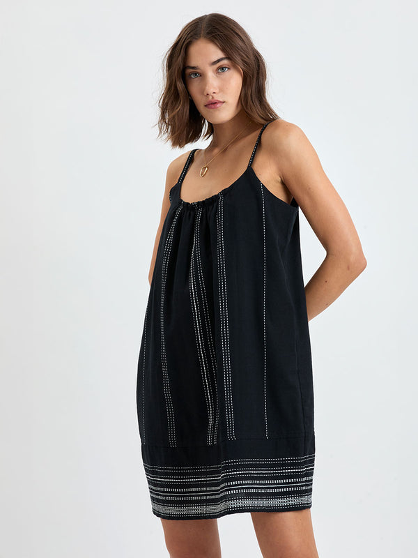 woman standing wearing lemlem handwoven ZINA Swing Dress dress featuring white dotted pattern in white color on black background