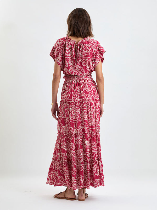 Back of a Woman Standing Wearing lemlem MUNA Crop Top and SANAA Skirt featuring rich burgundy fabric with white leaf print