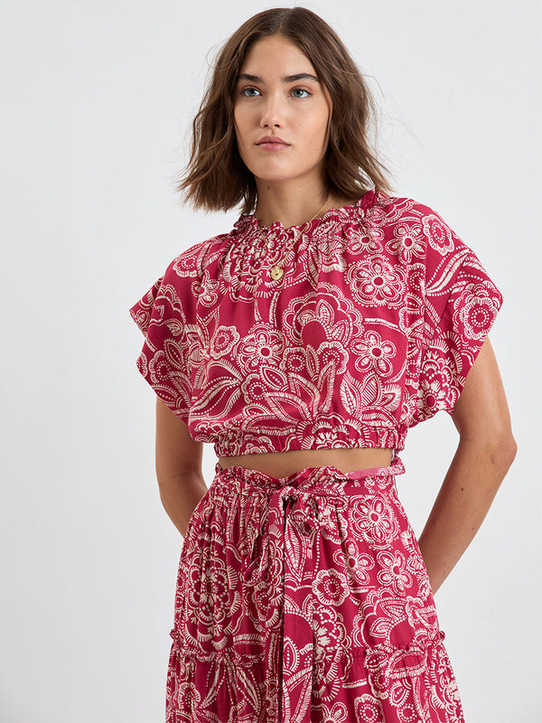 Woman Standing Wearing lemlem MUNA Crop Top and SANAA Skirt featuring rich burgundy fabric with white leaf print
