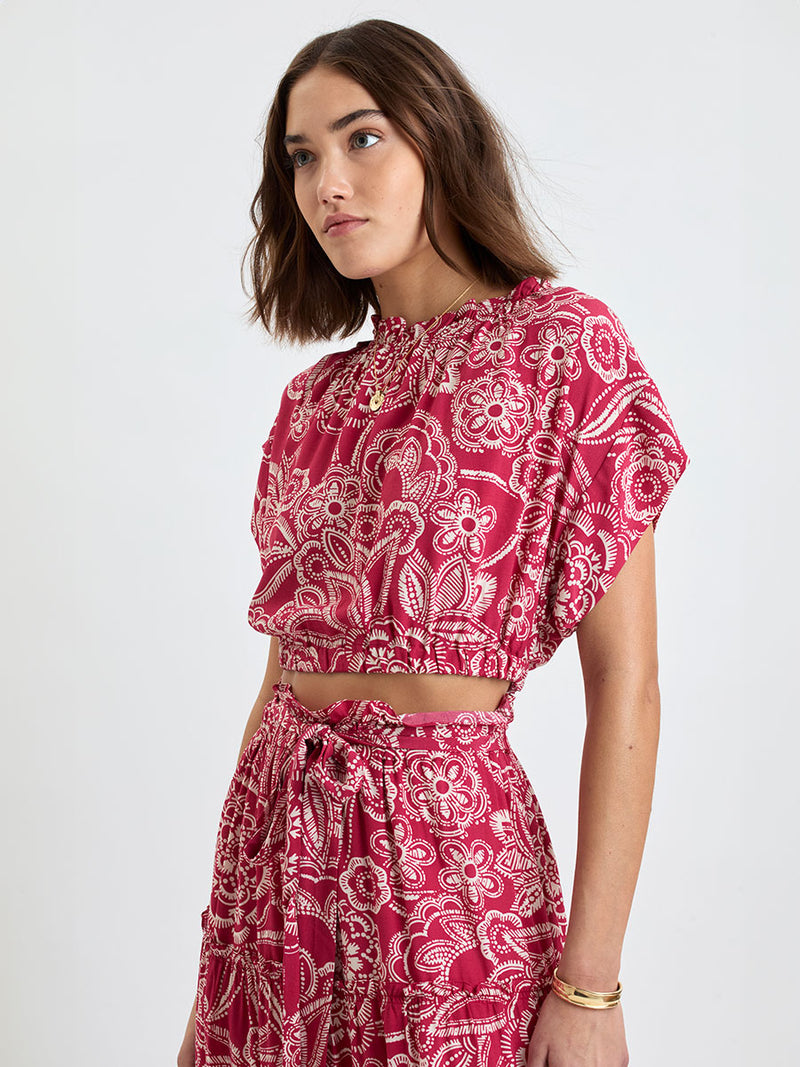 Woman Standing Wearing lemlem MUNA Crop Top and SANAA Skirt featuring rich burgundy fabric with white leaf print