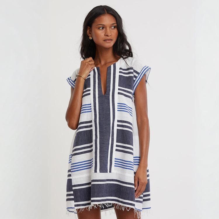 Woman standning wearing lemlem  ELINA handwoven caftan featuring navy striped pattern