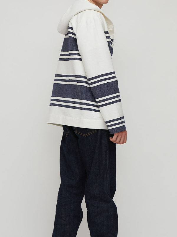 Man standing wearing lemlem handwoven ENDALK Jacket featuring navy stripe pattern on white background