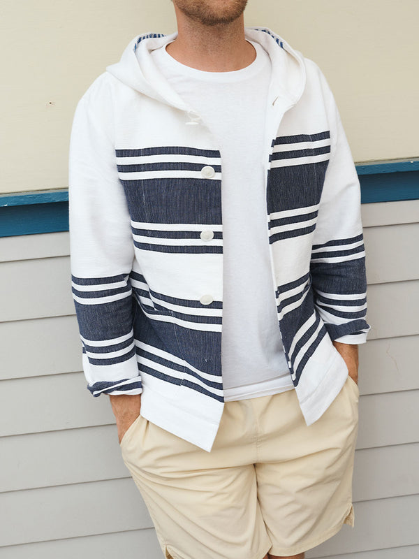 Man standing wearing lemlem handwoven ENDALK Jacket featuring navy stripe pattern on white background