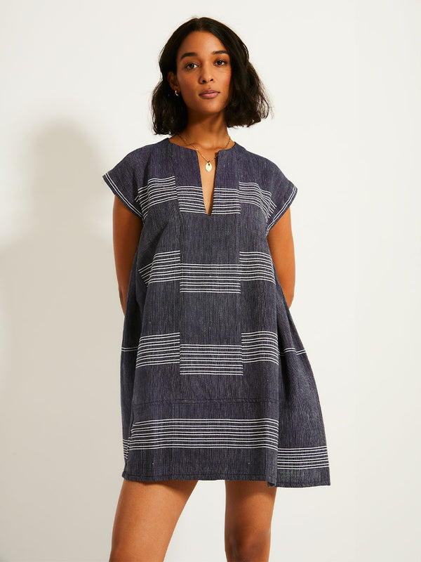 Woman Standing Wearing lemlem ELINA Caftan featuring chambray navy color accented with fine, textured white stripes
