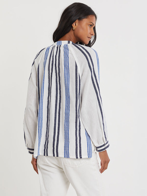 Woman wearing lemlem handwoven MITA Blouse featuring bold two-tone stripes in classic navy, blue colors on crispy white background.