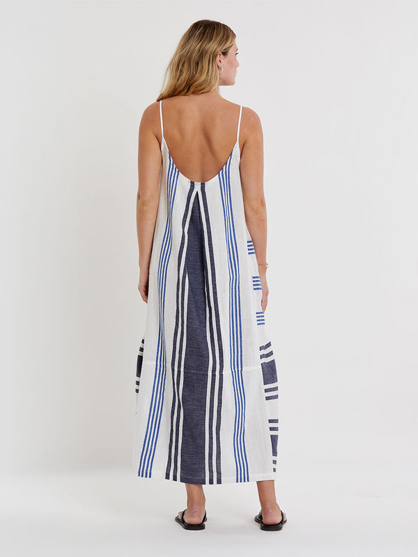 Woman wearing lemlem handwoven NIA Dress featuring bold two-tone stripes in classic navy, blue colors on crispy white background.
