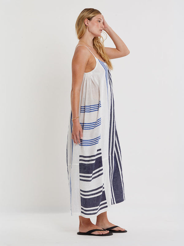 Woman wearing lemlem handwoven NIA Dress featuring bold two-tone stripes in classic navy, blue colors on crispy white background.