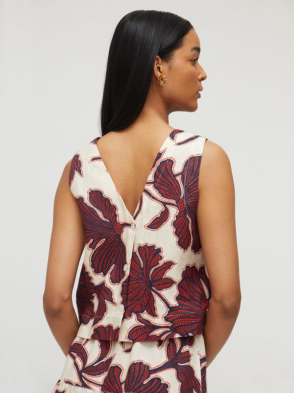 A woman shown from the back wearing a sleeveless wrap-style top with a deep V back and a bold floral print in dark red and navy on an off-white background.