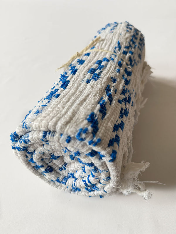 Product Shot of rolled lemlem Eshe Blue Rug featuring white and blue colors
