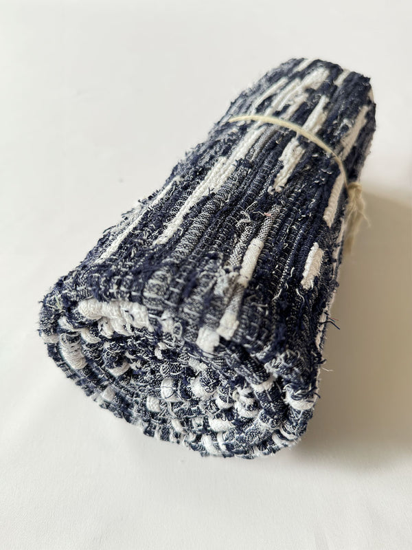 Product Shot of rolled lemlem Debre Navy Rug featuring white and navy colors