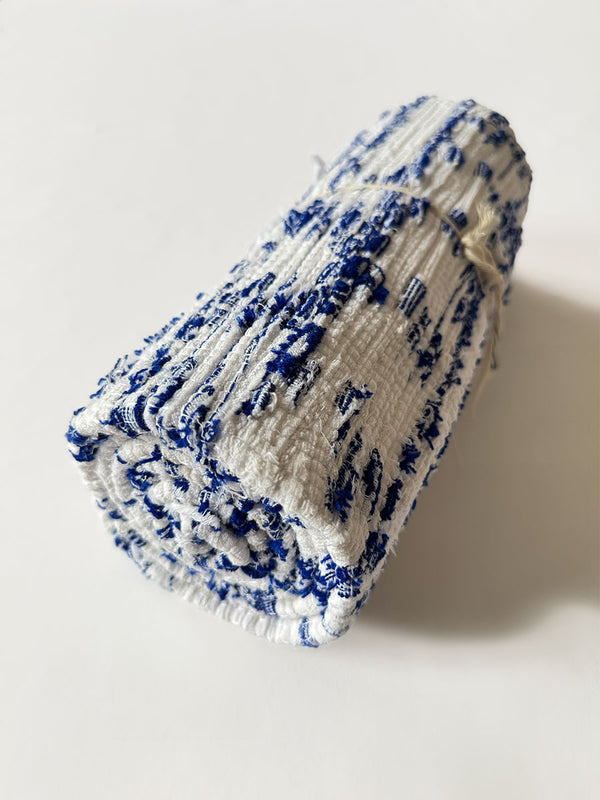 Product Shot of rolled lemlem Yani Blue Rug featuring white and blue colors