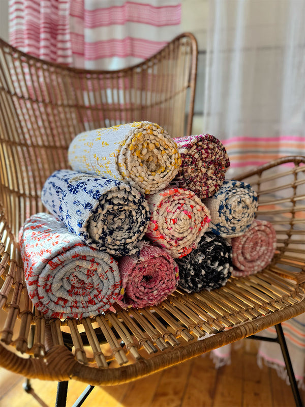 Shot of assorted rolled lemlem handwoven rugs placed on a straw chair