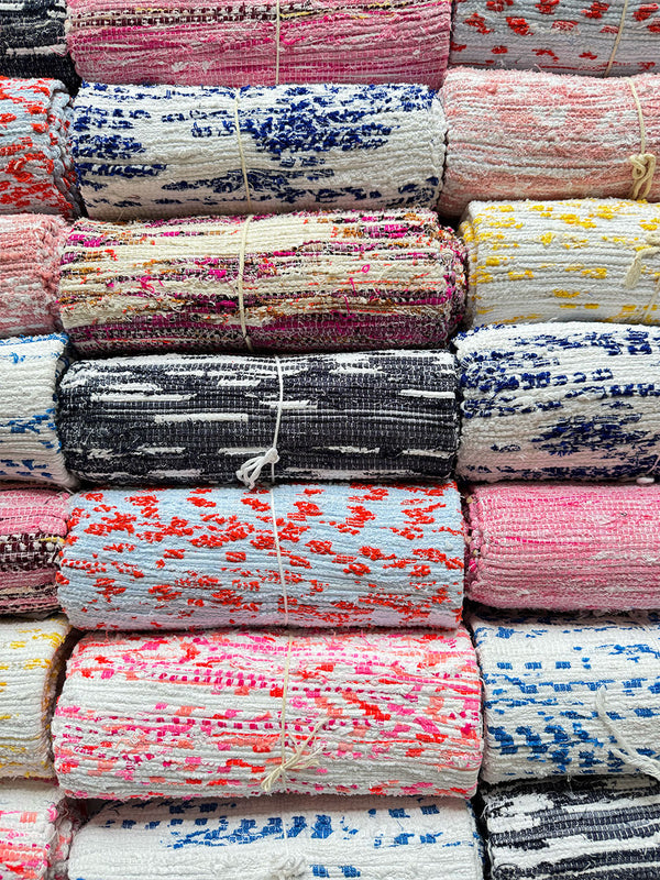 Shot of assorted rolled lemlem handwoven rugs 