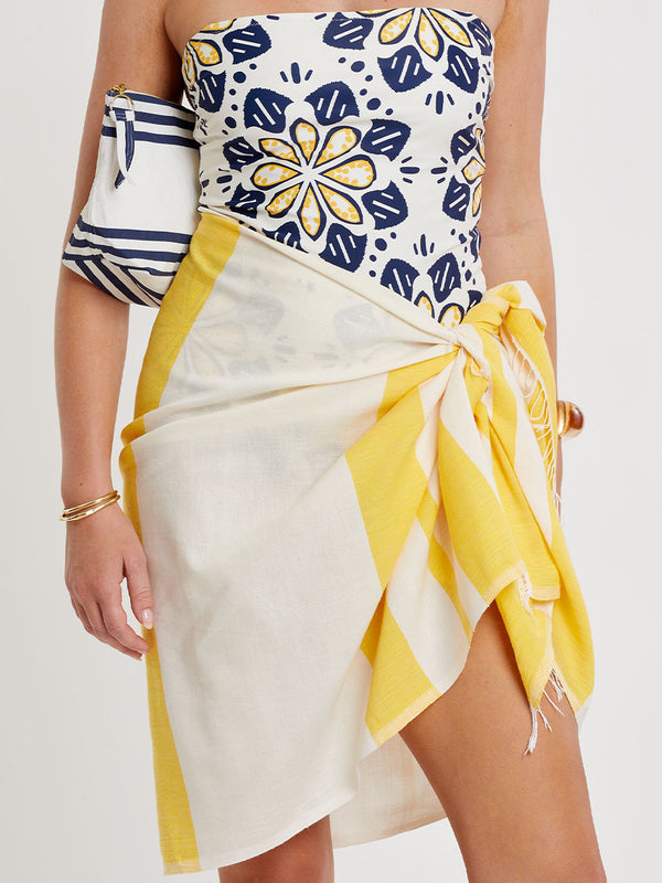Woman standing wearing lemlem handwoven LEMA Sarong featuring a wide block stripe pattern in rich yellow on a creamy vanilla background.