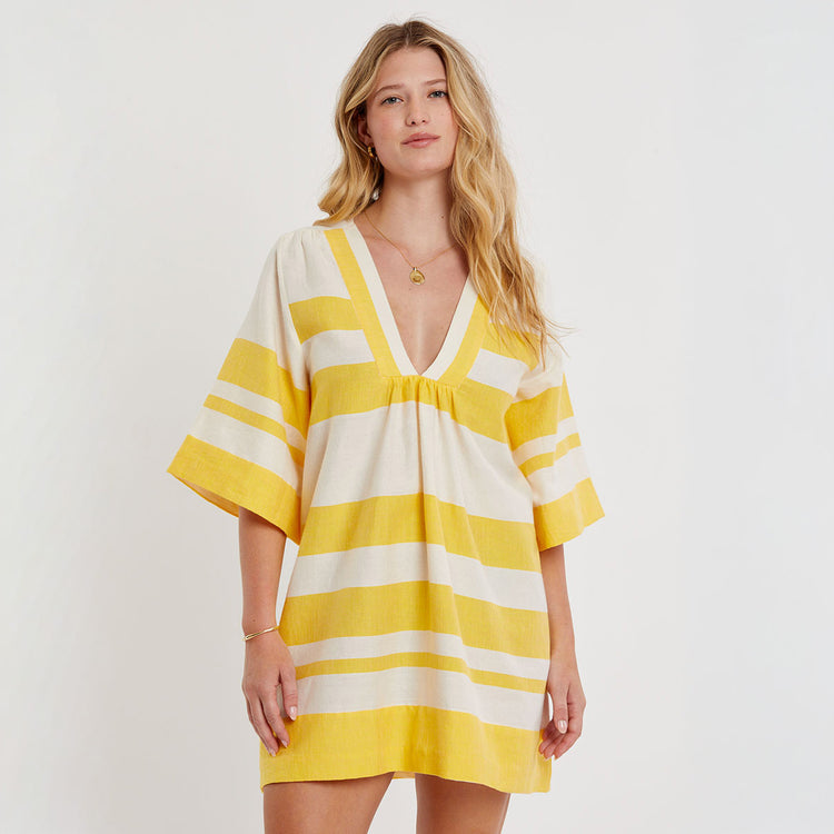 Woman wearing a yellow and white striped dress on a plain background