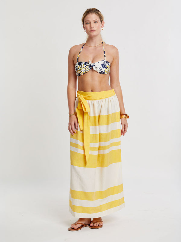 Woman standing wearing lemlem handwoven TOLA Skirt featuring a wide block stripe pattern in rich yellow on a creamy vanilla background.