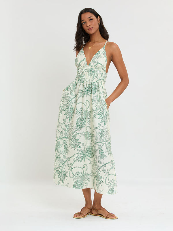 Woman Standing wearing lemlem GETE Dress featuring a custom, hand-drawn tropical pineapple motif in a tropical green hue on an ivory background.