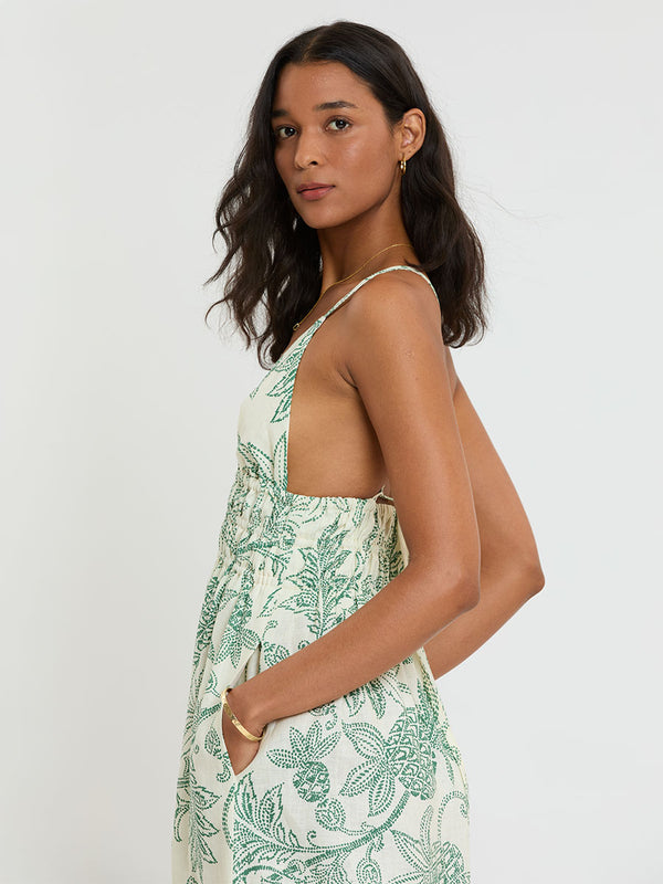 Woman Standing wearing lemlem GETE Dress featuring a custom, hand-drawn tropical pineapple motif in a tropical green hue on an ivory background.