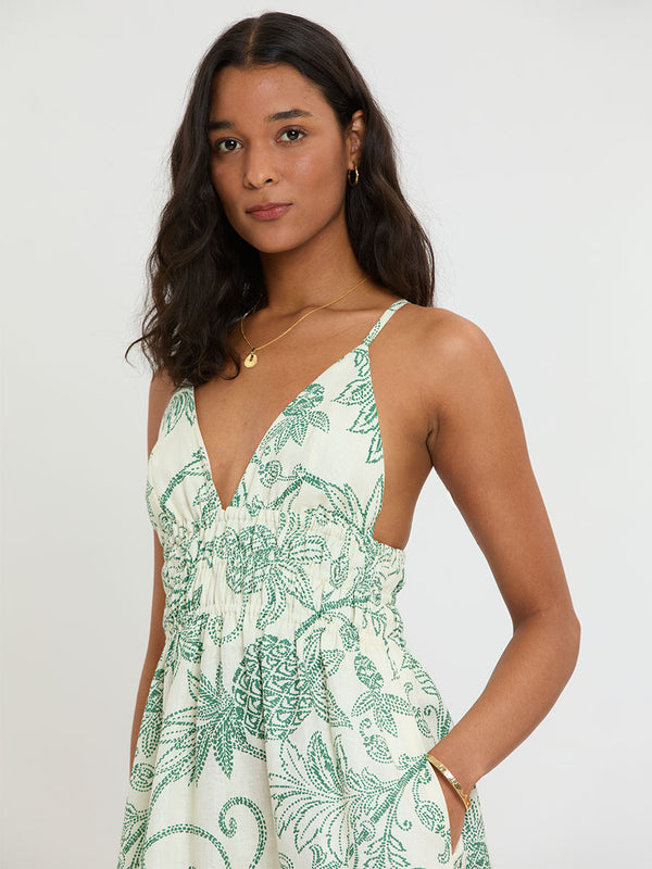 Woman Standing wearing lemlem GETE Dress featuring a custom, hand-drawn tropical pineapple motif in a tropical green hue on an ivory background.