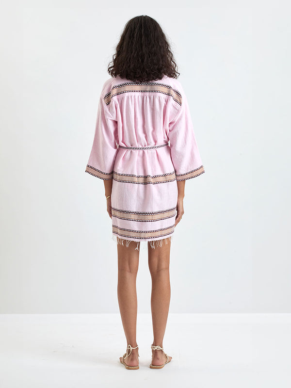 back of a Woman Standing wearing lemlem IMANI Robe and DINHA One Piece featuring detailed bands of deep burgundy, bronze, and pink stripes beautifully placed on a light cream 