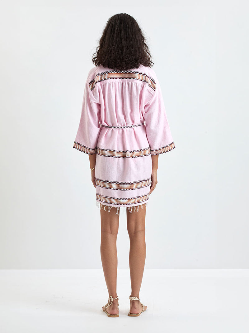 back of a Woman Standing wearing lemlem IMANI Robe and DINHA One Piece featuring detailed bands of deep burgundy, bronze, and pink stripes beautifully placed on a light cream 