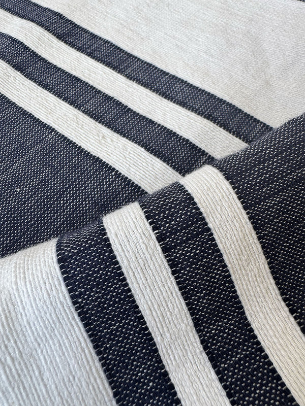 Close up on lemlem handwoven fabric featuring stripe navy pattern on white crispy background