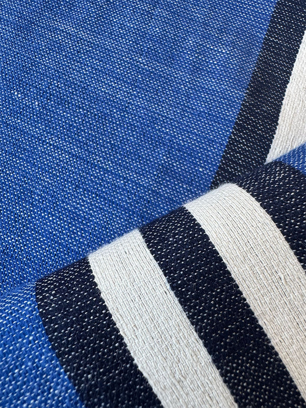 Close-up of a woven textile with a bright blue field and bold black-and-white diagonal stripes.