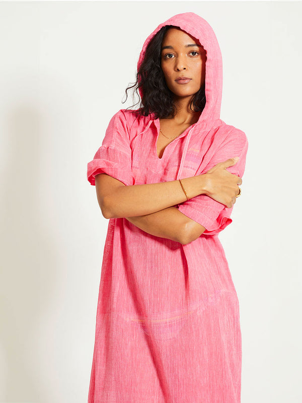 Woman Standing Wearing lemlem BERITU | Hoodie Dress featuring sheer fabric in pink watermelon color