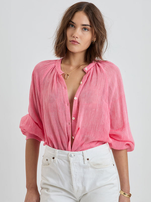 Woman Standing Wearing lemlem MITA | Button Up Blouse featuring sheer fabric in pink watermelon color