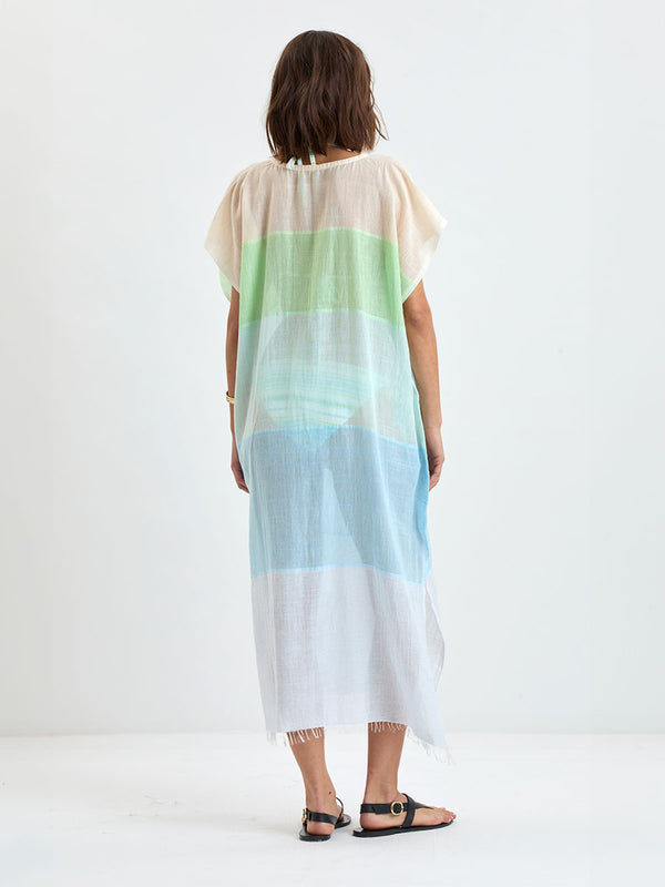 Back of a a woman standing wearing DALILA Caftan featuring light blue, aqua, mint, soft green and cream
