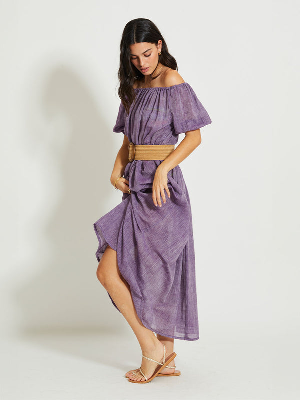 Side SHot of a Woman Standing Wearing lemlem RAHEL | Off Shoulder Dress featuring sheer fabric in rich plum color