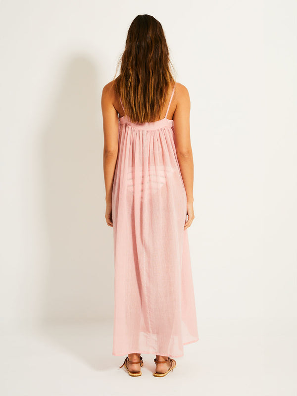 Back of a Woman Standing Wearing lemlem EDA Slip Dress featuring sheer fabric in soft rose color

