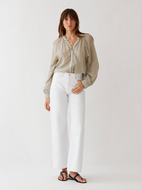 Woman standing wearing lemlem MITA Blouse featuring sheer handwoven fabric in sage color