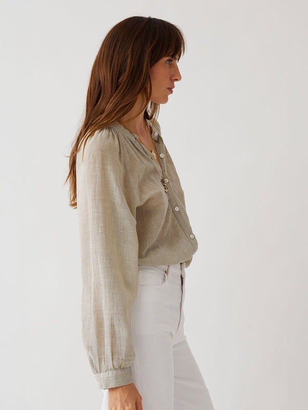 Woman standing wearing lemlem MITA Blouse featuring sheer handwoven fabric in sage color