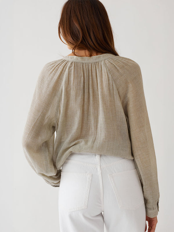 Woman standing wearing lemlem MITA Blouse featuring sheer handwoven fabric in sage color