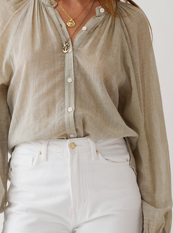 Woman standing wearing lemlem MITA Blouse featuring sheer handwoven fabric in sage color