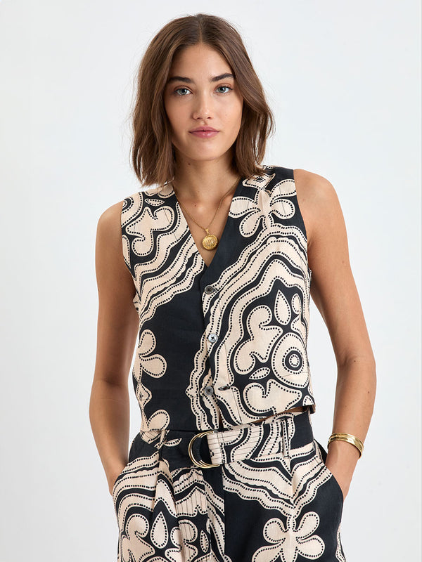  Woman Standing wearing lemlem linen ADOWA Shell Tank Top  featuring  a custom-designed print inspired by ancient architectural patterns in cream and black colors and matching pants