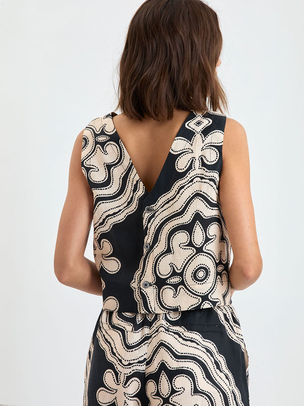Back of a Woman Standing wearing lemlem linen ADOWA Shell Tank Top  featuring  a custom-designed print inspired by ancient architectural patterns in cream and black colors and matching pants