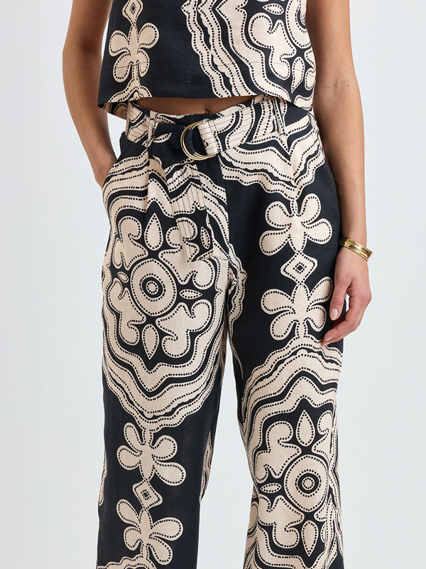 Close up on a woman standing wearing lemlem DIRARRA Pants featuring ancient inspired pattern in cream color on black background and a matching tank top
