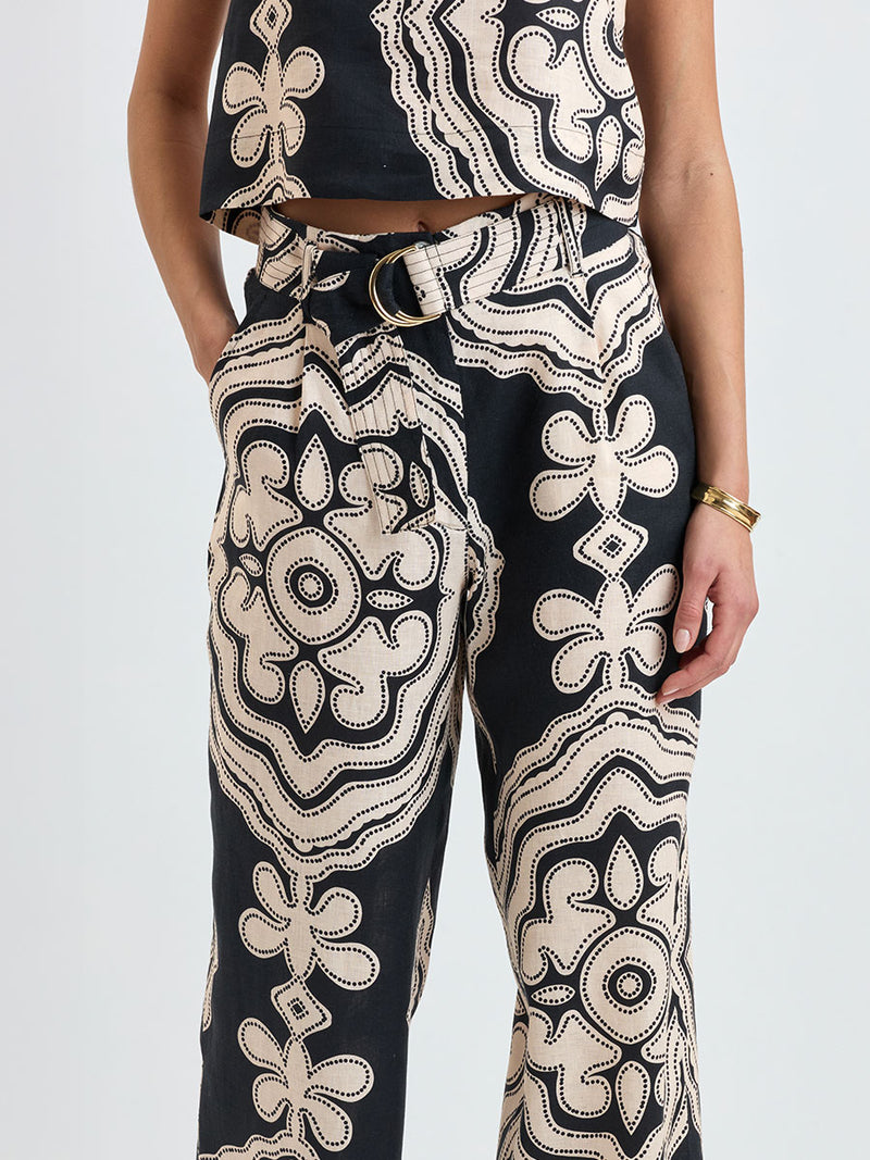 Close up on a woman standing wearing lemlem DIRARRA Pants featuring ancient inspired pattern in cream color on black background and a matching tank top