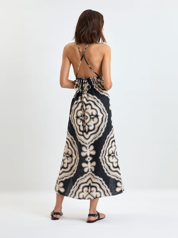 Woman's back shot Standing wearing lemlem linen GETE  Triangle  Dress  featuring  a custom-designed print inspired by ancient architectural patterns in cream and black colors